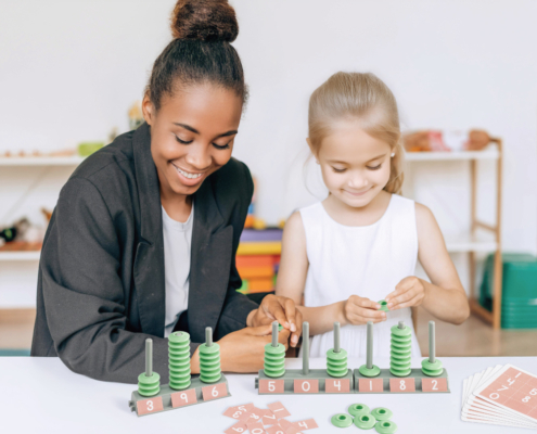 Children and a teacher or a parent are using Green-n-Learn® Place Value Abacus together to learn numeracy.