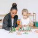 Children and a teacher or a parent are using Green-n-Learn® Place Value Abacus together to learn numeracy.